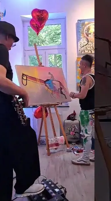 Easel painting, guitar – Art Is Trash urban art in Düsseldorf Painting on an easel beside a guitarist in a bright studio with heart balloons, Düsseldorf, Art Is Trash